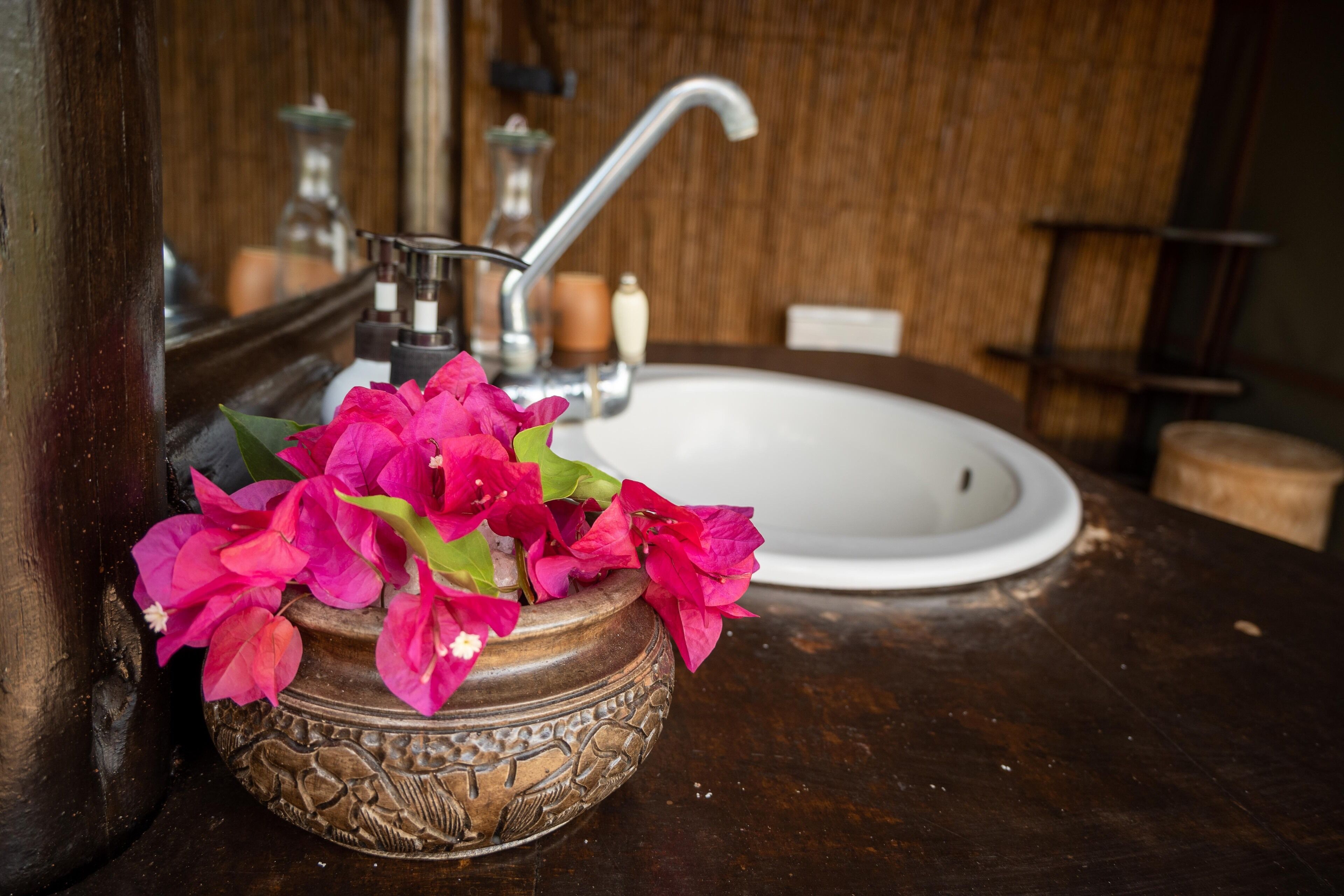 A bathroom with a wooden vanity, a white sink, and a decorative bowl with pink flowers.