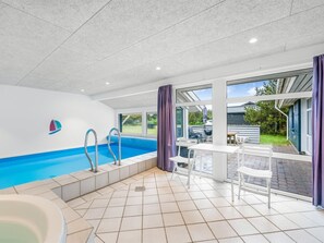 Ein Pool mit Blick ins Freie, ein Tisch mit Stühlen und eine Badewanne.