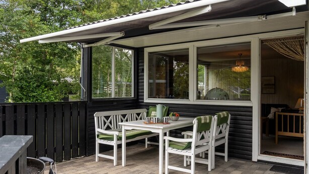 Eine Terrasse mit Tisch, Stühlen, einem Grill und Blick auf die Umgebung.