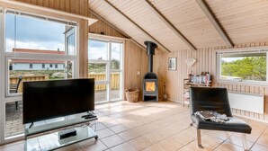 A cozy living room with a fireplace, large windows, and a TV on a glass table. - "Skev" - 200m to the fjord by Interhome (Hvide Sande)