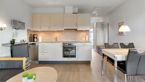 A modern kitchen with white cabinets, a built-in oven, and a dining area with a table and chairs.