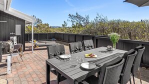 An outdoor patio with a dining table, chairs, and a grill.