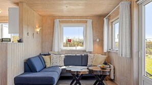 A cozy cabin interior with a blue sofa, a small wooden table, and a window with a flag.