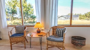A room with two wicker chairs, a small table with a lamp, and a large window with curtains. - "Jules" - 300m from the sea by Interhome (Fanø)