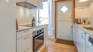 A modern kitchen with white cabinets, a built-in oven, a coffee maker, and a view through a window. - "Jules" - 300m from the sea by Interhome (Fanø)