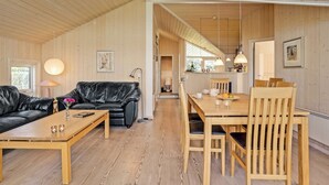 A spacious living area with a wooden floor, a black leather sofa, a wooden coffee table, and a dining table with chairs. - "Brynjolf" - 350m to the fjord by Interhome (Vinderup)