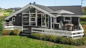 A modern house with a large deck, a covered outdoor seating area, and a view of the surrounding landscape. - "Brynjolf" - 350m to the fjord by Interhome (Vinderup)