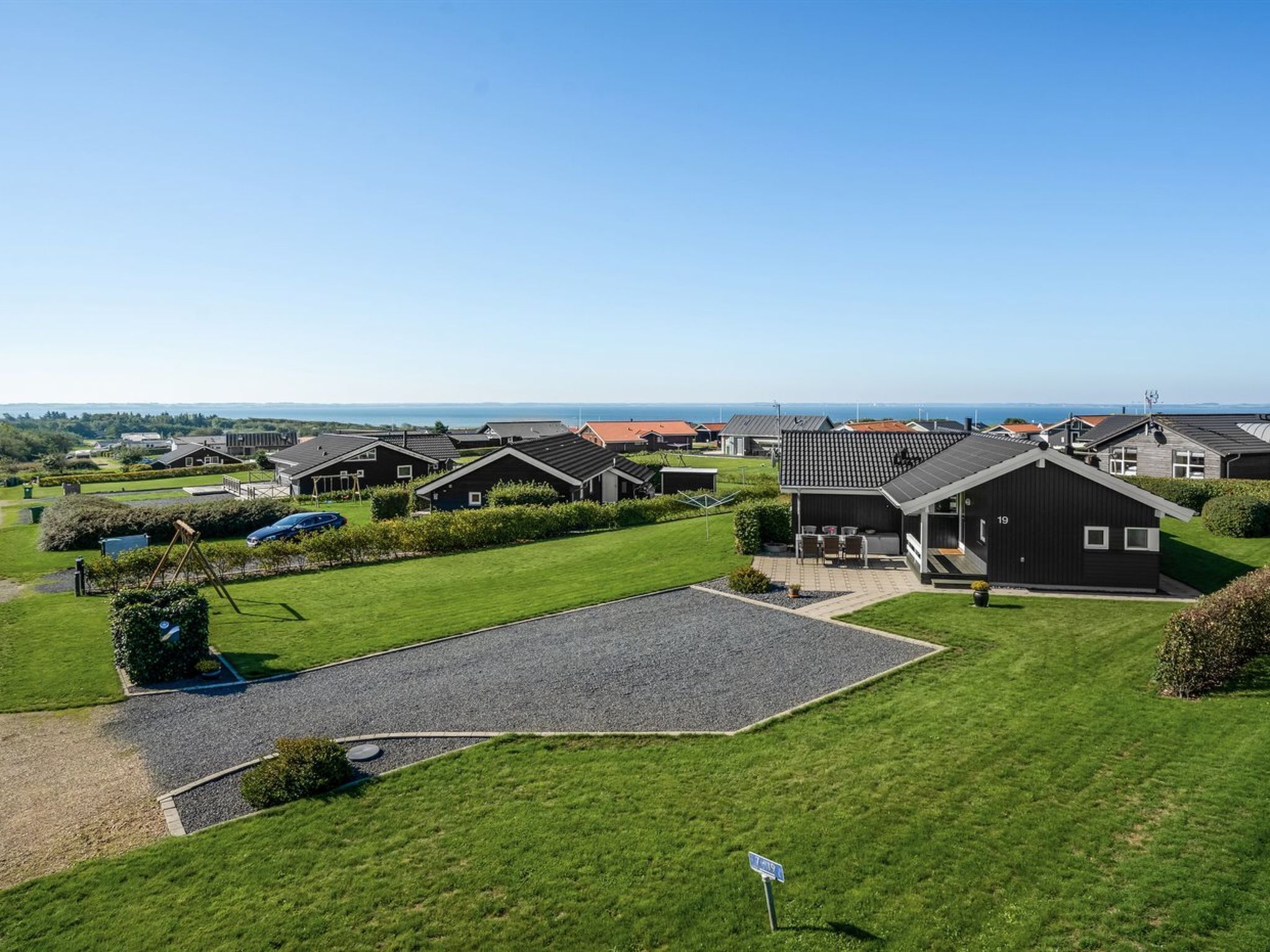 Un quartier résidentiel avec des maisons modernes, un ciel dégagé et une vue sur la mer.