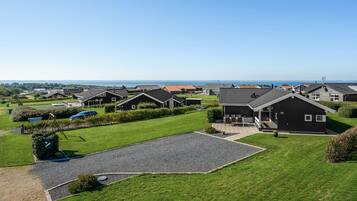 Un quartier résidentiel avec des maisons modernes, un ciel dégagé et une vue sur la mer.