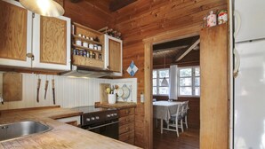 A wooden cabin kitchen with a central island, wooden cabinets, and a dining area with a table and chairs.