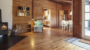 A cozy log cabin interior with a fireplace, wooden walls, a dining area, and a comfortable seating space.