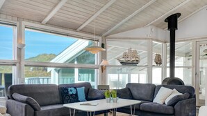 A modern living room with a grey sofa, white coffee table, and a large window offering a view of the outdoors.