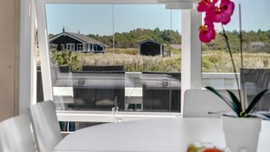 A room with a large window offering a view of a house and surrounding landscape.