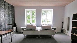A bedroom with a bed, two windows, a chair, a table, and a TV. - "Thia" - 4km to the fjord by Interhome (Aabenraa)
