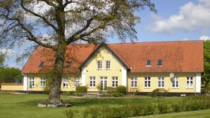 A yellow building with a red roof, surrounded by a well-maintained lawn and a large tree. - "Thia" - 4km to the fjord by Interhome (Aabenraa)
