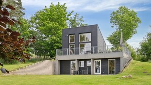 A modern two-story house with a balcony, a staircase leading to the upper level, and a grassy yard. - "Harka" - 100m to the fjord by Interhome (Roskilde)