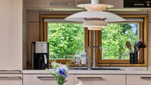 A modern kitchen with a coffee maker, a sink, and a window with a view of greenery. - "Harka" - 100m to the fjord by Interhome (Roskilde)
