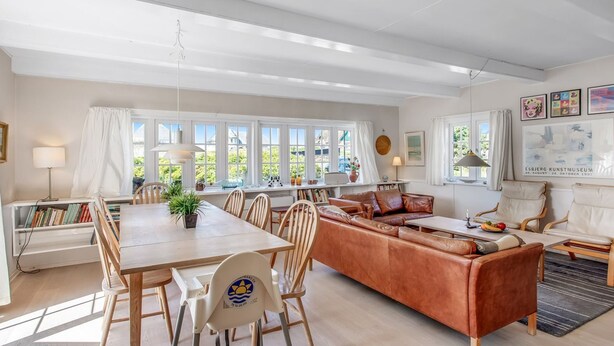 Ein geräumiges Wohnzimmer mit großem Holzesstisch, Ledersofa und verschiedenen Sitzgelegenheiten.
