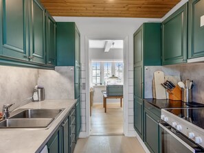 Een koelkast, een oven, een vaatwasser, kookgerei, borden en bestek