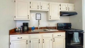 Una cocina con gabinetes blancos, una estufa negra y una encimera de madera.
