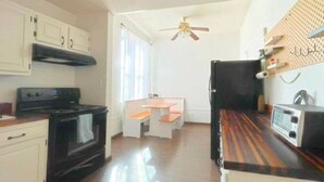 Una cocina con estufa, horno, microondas y ventilador de techo.
