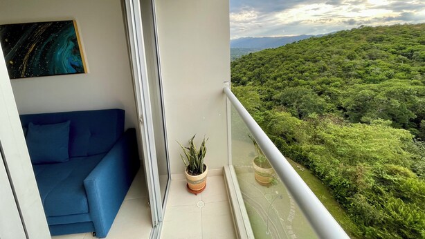 Ein Balkon mit einem blauen Sofa, einem Gemälde und einem Blumentopf.
