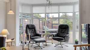 A sunlit room with two leather chairs, a small table, and a lamp.