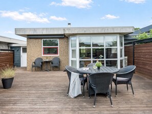 A wooden deck with a round table and chairs, a small window, and a door. - "Sighmar" - 900m from the sea by Interhome (Blåvand)