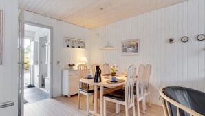 Uma sala de jantar com uma mesa e cadeiras de madeira, uma luminária e um quadro na parede.