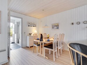 Un coin repas avec une table et des chaises en bois, une lampe et un tableau au mur.