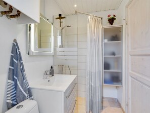 A modern bathroom with a shower, a sink, a toilet, and a mirror. There is a towel hanging on the wall and a small plant on the shelf. - "Sighmar" - 900m from the sea by Interhome (Blåvand)