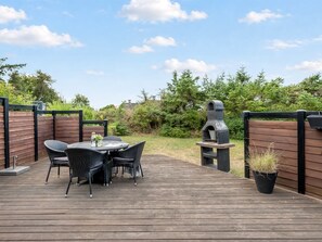 A wooden deck with a round table and chairs, a barbecue grill, and a potted plant. - "Sighmar" - 900m from the sea by Interhome (Blåvand)