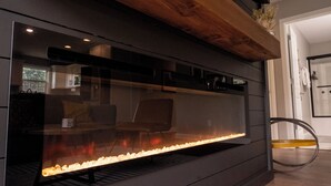 A modern fireplace with a glass front, wooden mantel, and a built-in seating area.