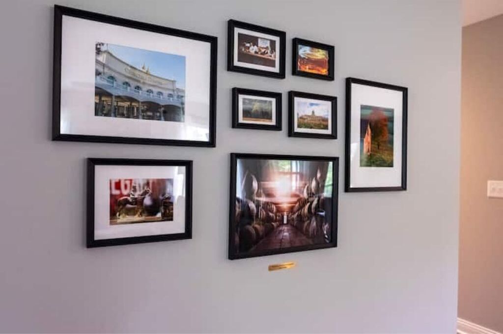 En vägg med åtta inramade fotografier som föreställer olika motiv, bland annat arkitektur och landskap.