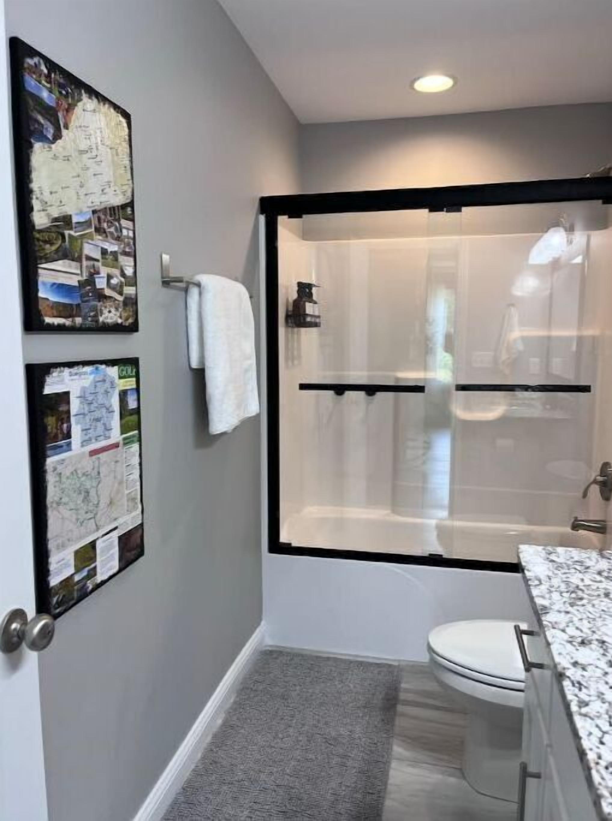 Un baño moderno con cabina de ducha de vidrio, inodoro y lavamanos con encimera de mármol.