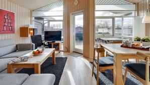 Ein modernes Wohnzimmer mit Sofa, Couchtisch, Fernseher und Essbereich mit Stühlen und Tisch.