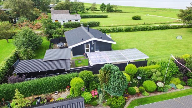 A residential property with a large lawn, a solar panel on the roof, and a view of a lake. - "Ilya" - 90m to the fjord by Interhome (Storvorde)