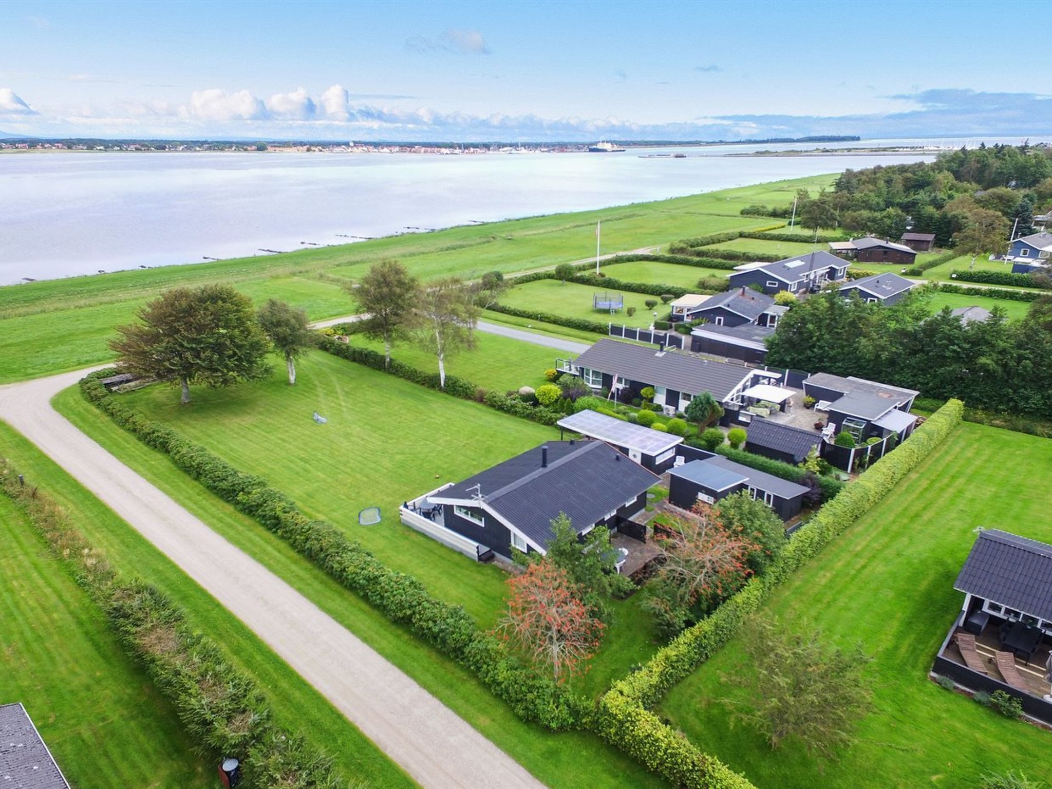 A residential area with houses, a road, and a body of water in the background.