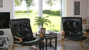 A room with two black leather chairs, a small wooden table, and a potted plant. - "Ilya" - 90m to the fjord by Interhome (Storvorde)
