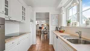 Una cocina moderna con armarios blancos, un lavamanos de acero inoxidable y una ventana con vistas a una zona residencial.