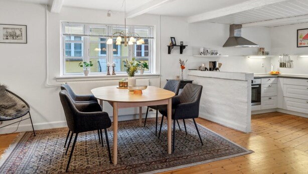 Een moderne keuken met witte kasten, een centraal eiland en een eethoek met een ronde tafel en stoelen.