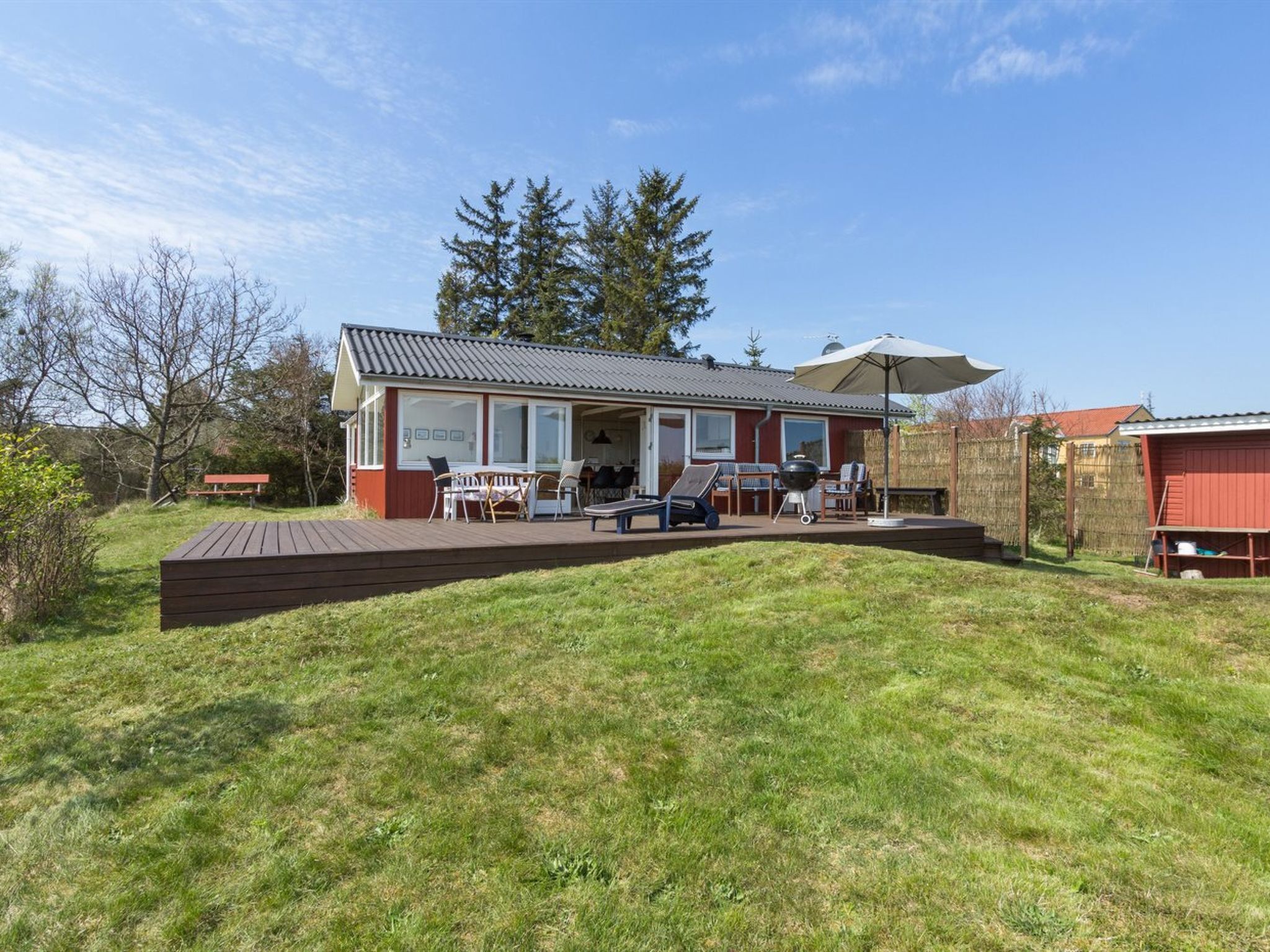 A house with a deck, outdoor seating, and a barbecue area.