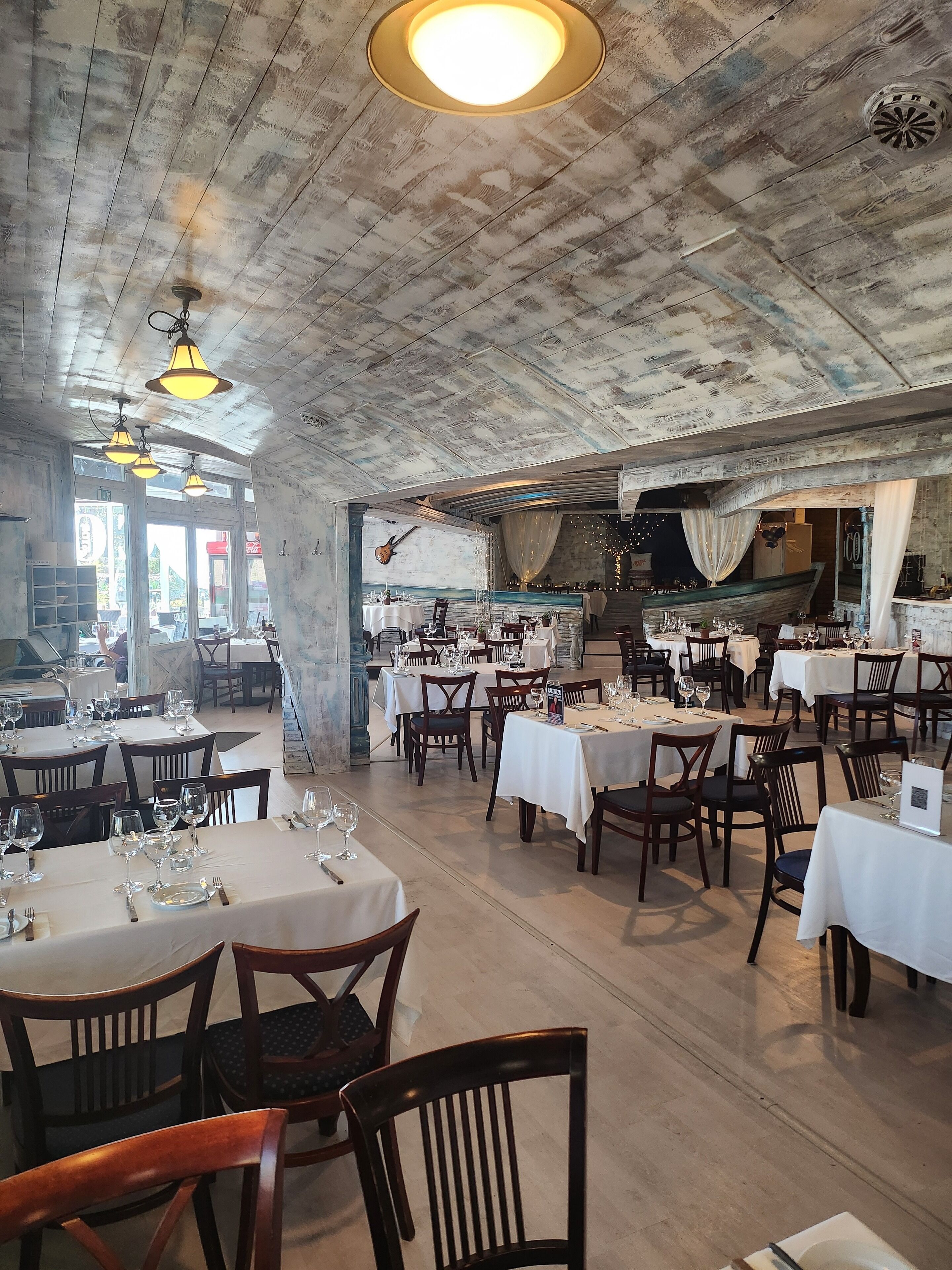 A restaurant with wooden ceiling and tables set for dining.