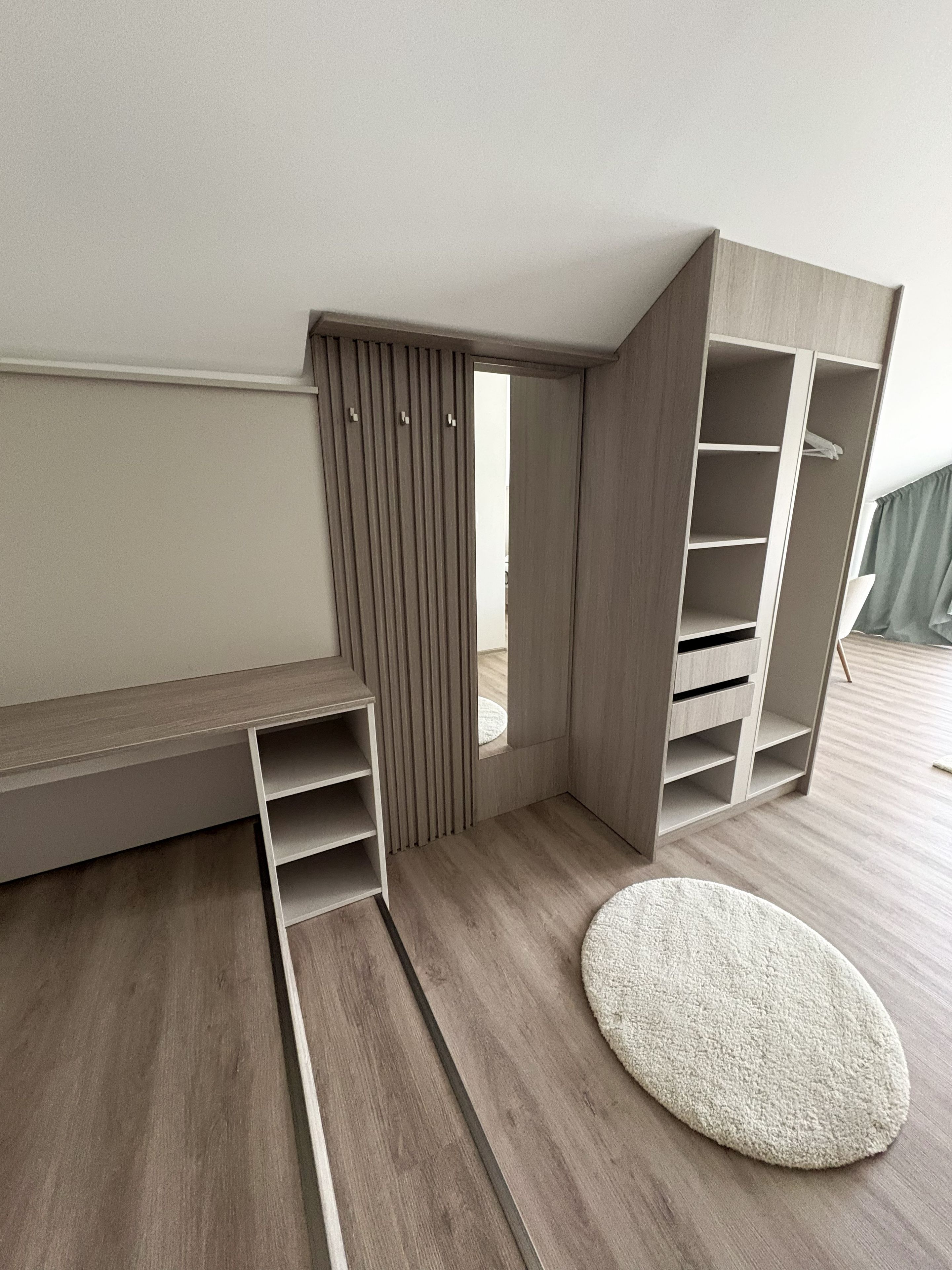 Una habitación con un banco empotrado, un tapete circular y un armario con estantes múltiples.