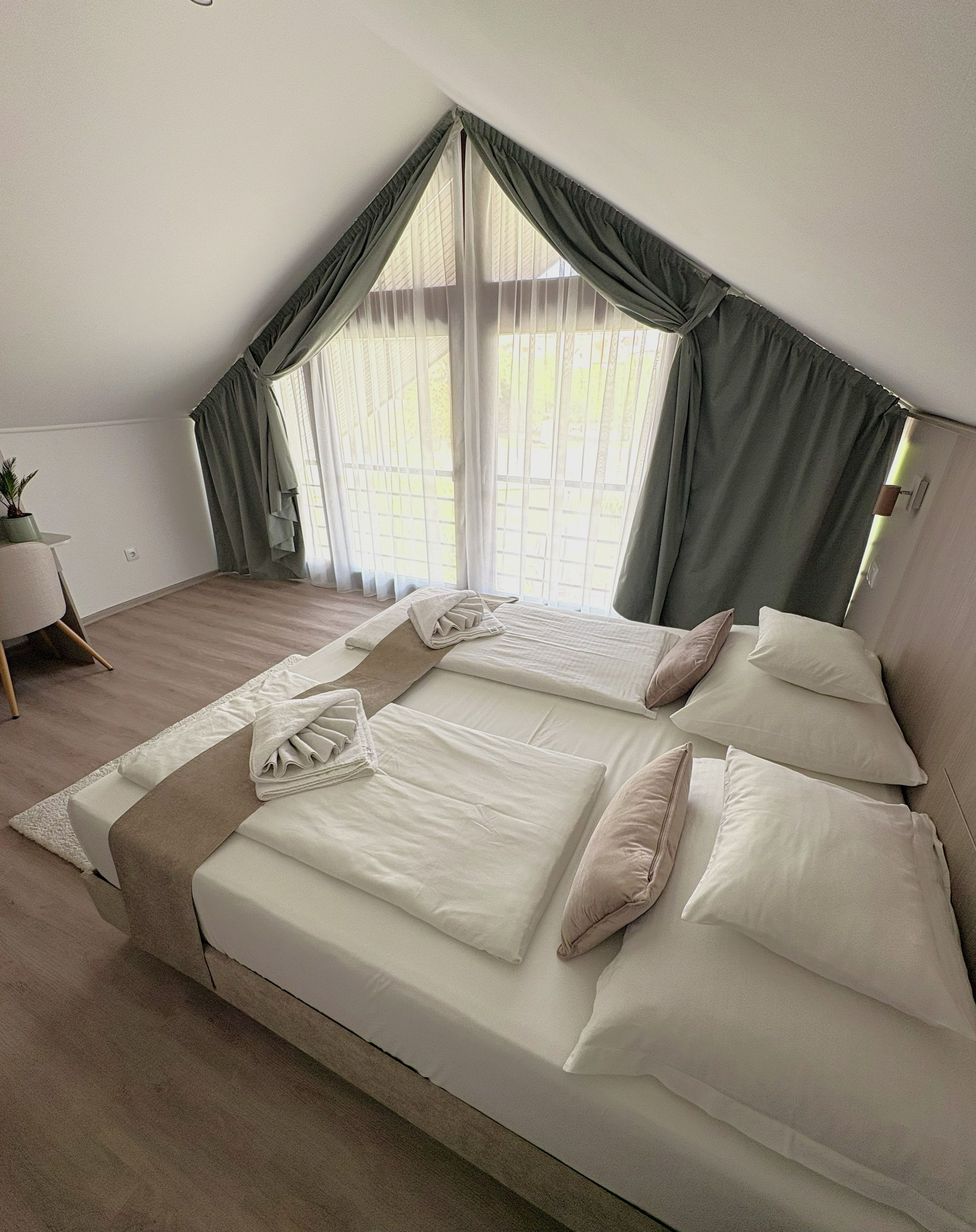 A bedroom with a large bed, a bedside table, and a window with curtains.