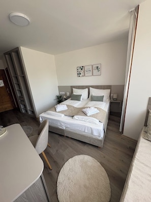 Un dormitorio con cama, mesitas de noche, escritorio y silla.