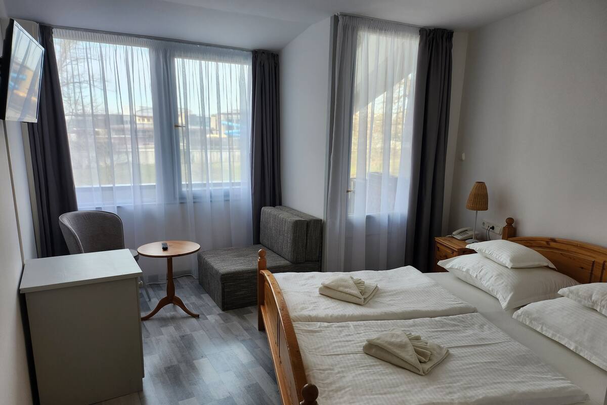 Ein Hotelzimmer mit zwei Betten, einem Schreibtisch, einem Stuhl, einem kleinen Tisch und einer Lampe.