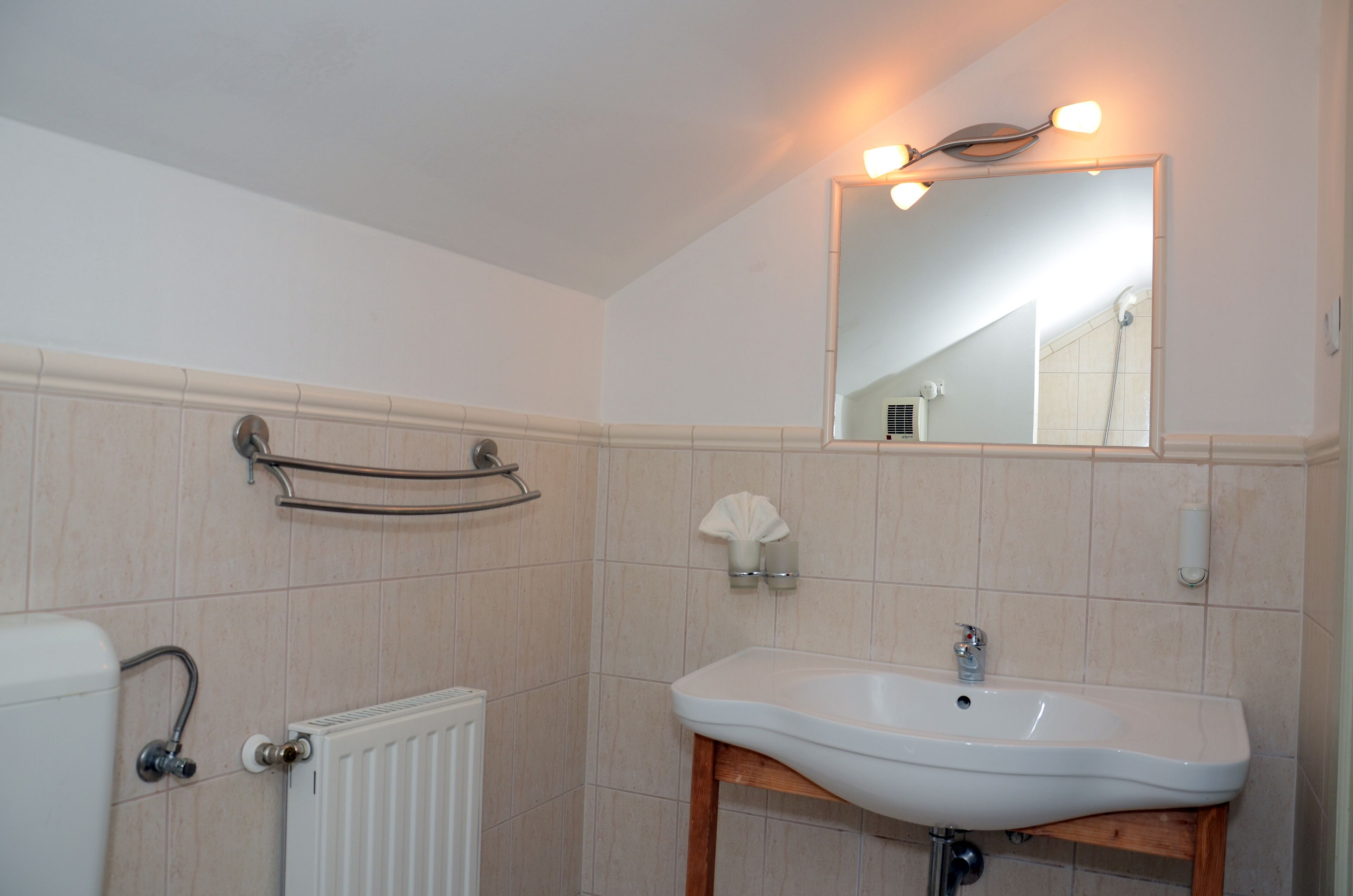 A bathroom with a white sink, a mirror, and a towel rack.