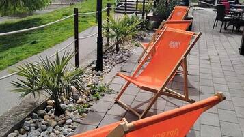 Outdoor seating with orange chairs, a lamp post, and a pathway lined with plants and rocks.