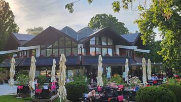 A modern building with a dining area featuring outdoor seating and umbrellas.